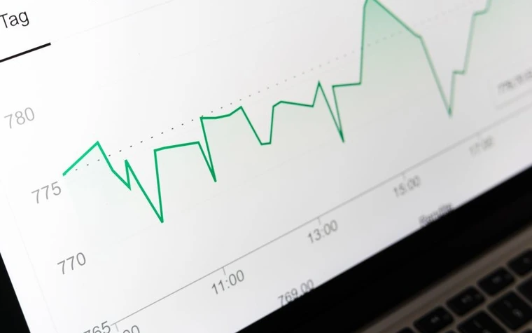 A green line chart trending upward on a laptop screen, similar to how a betting line moves toward game time