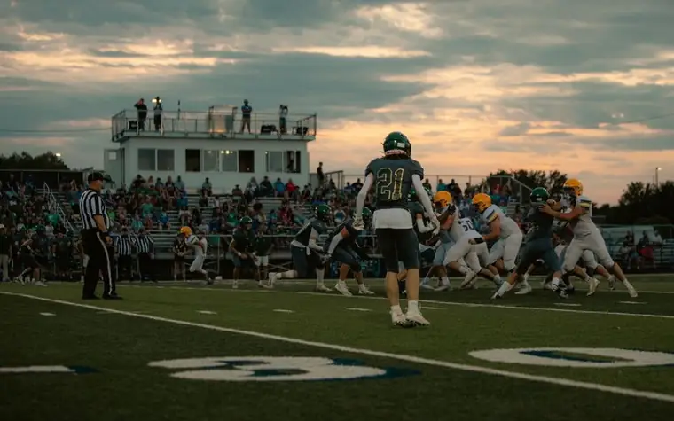 Football players in action under stadium floodlights at night during a live game