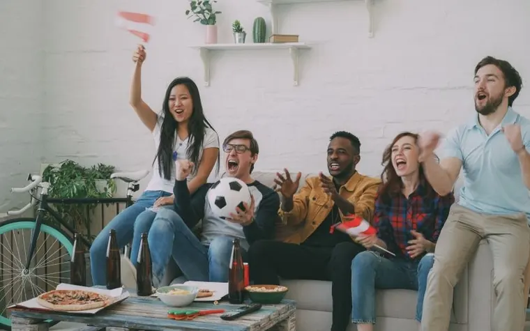 A group of friends cheering while watching a sports game together at home