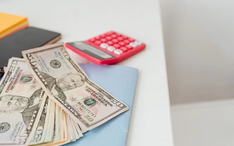 Notebook, cash, and a red calculator arranged on a desk for working out betting math