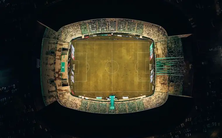 Aerial view of a floodlit soccer stadium and pitch at night
