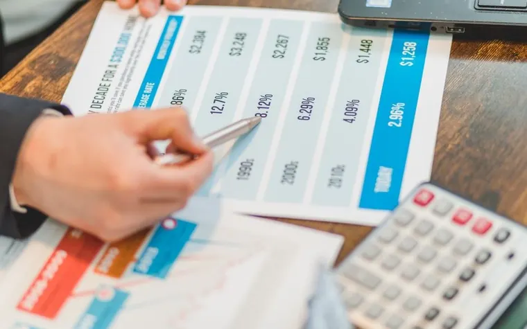 Close-up of financial documents with printed charts next to a calculator