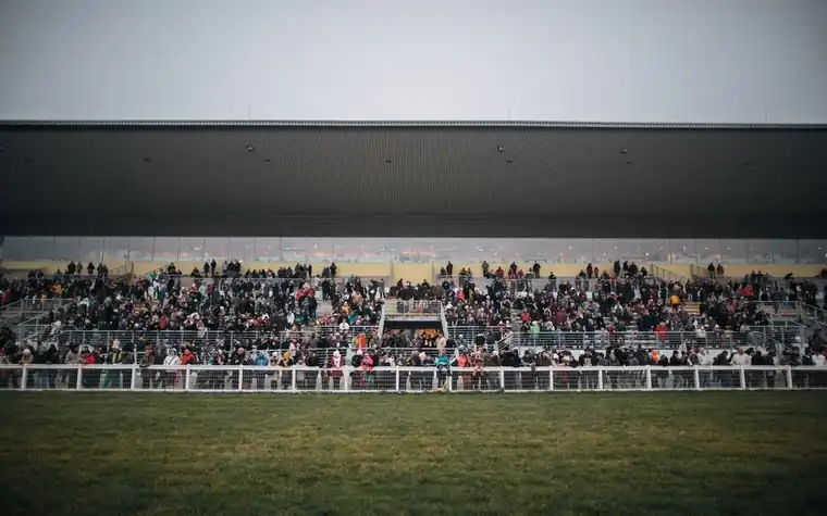 Spectators filling a grandstand overlooking a horse racing track