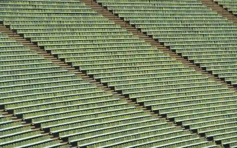 Rows of empty green stadium seats arranged in a diagonal symmetrical pattern