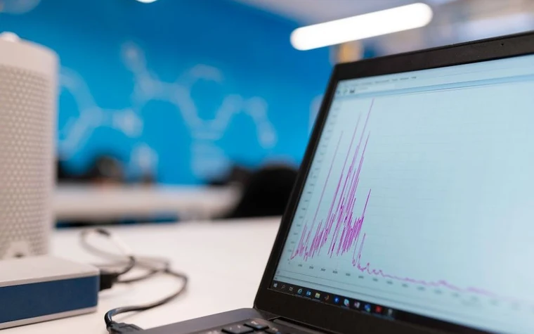 A laptop screen displaying a jagged purple line chart with sharp spikes settling into a flatter trend