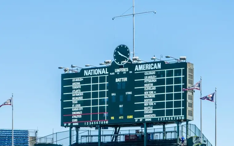 Illuminated scoreboard showing team names and game details above a stadium entrance