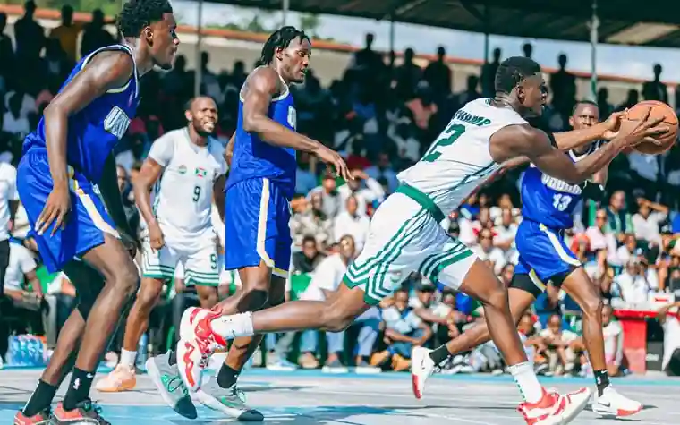 Basketball players competing under bright stadium lights in front of a crowded arena
