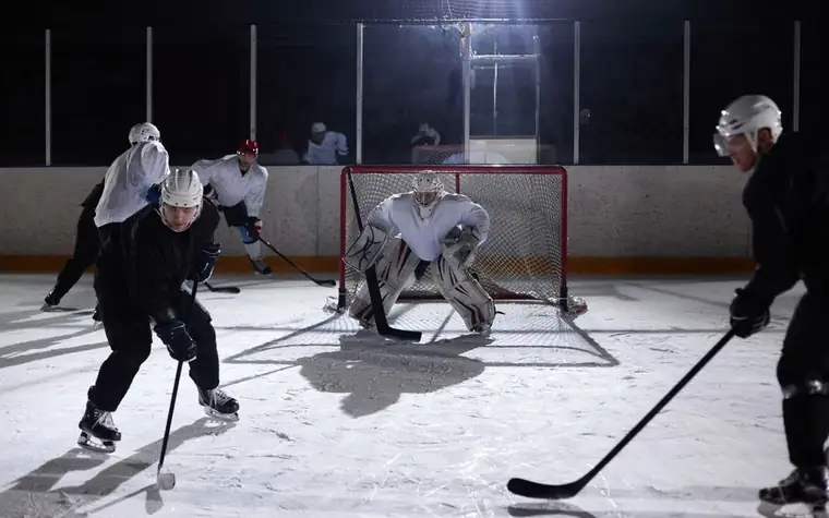 Ice hockey goalie defending the net as an attacking player closes in on a breakaway