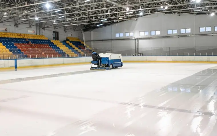 Empty ice hockey rink with colorful stadium seating as a Zamboni resurfaces the ice sheet