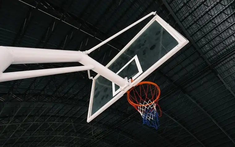 Close-up of an indoor basketball hoop and white backboard in an empty gymnasium