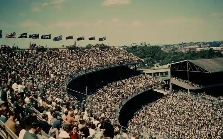 vintage photograph of a huge packed crowd filling the curved stands of a large sports stadium on a sunny day