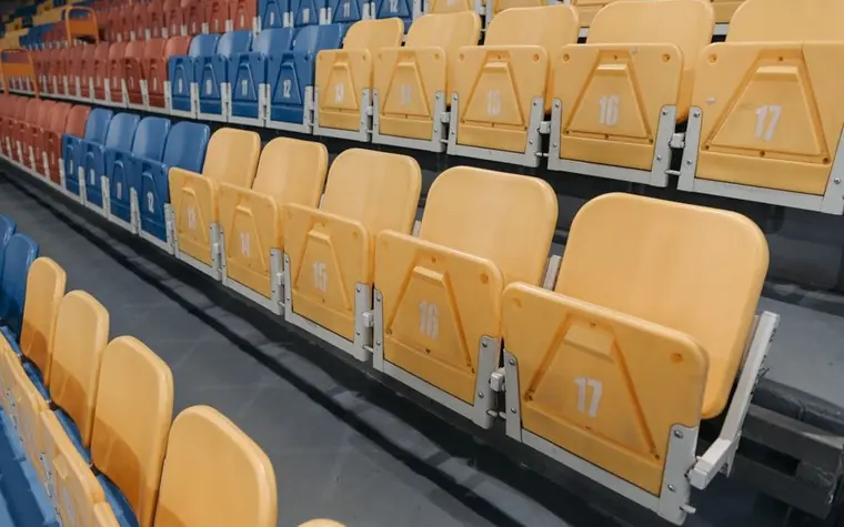 Rows of empty yellow and blue stadium seats viewed from an angle
