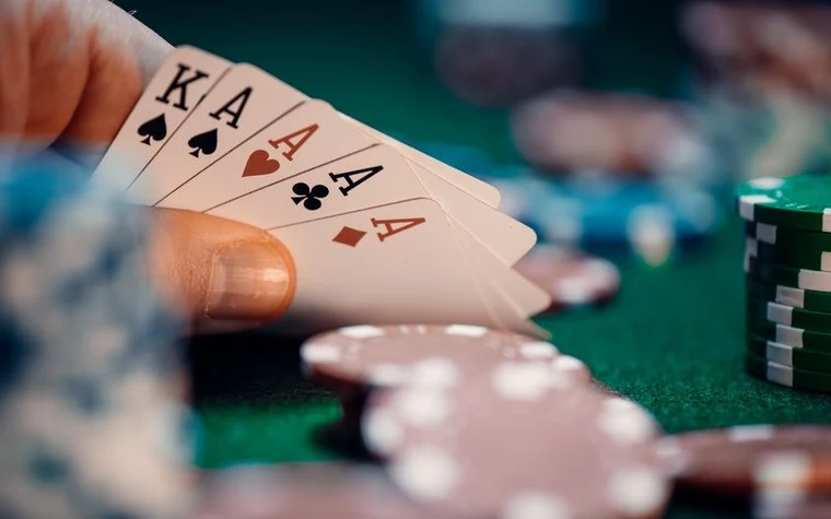 Close-up of a poker hand holding four aces and a king with casino chips on the table