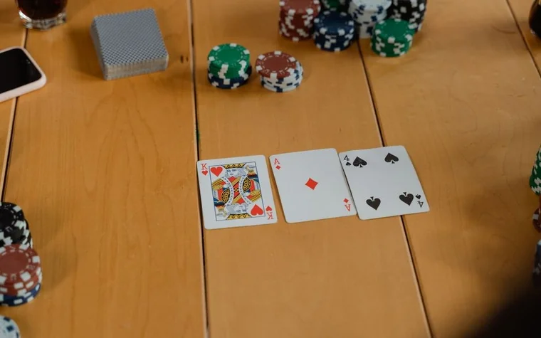 Three playing cards, a king, an ace, and a four, dealt face up next to stacked casino chips