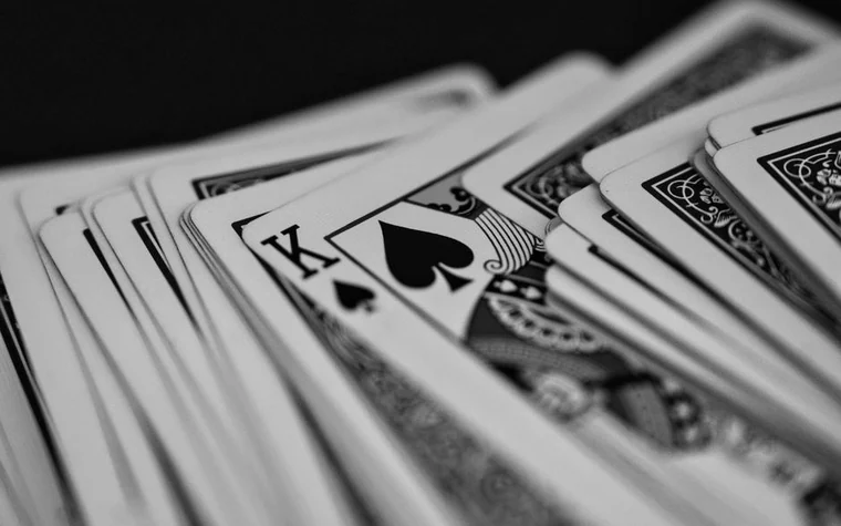 A fanned deck of playing cards in black and white with the king of spades face up