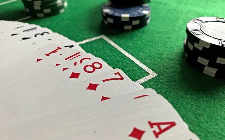 Close-up of playing cards fanned out next to stacked poker chips on a green felt table