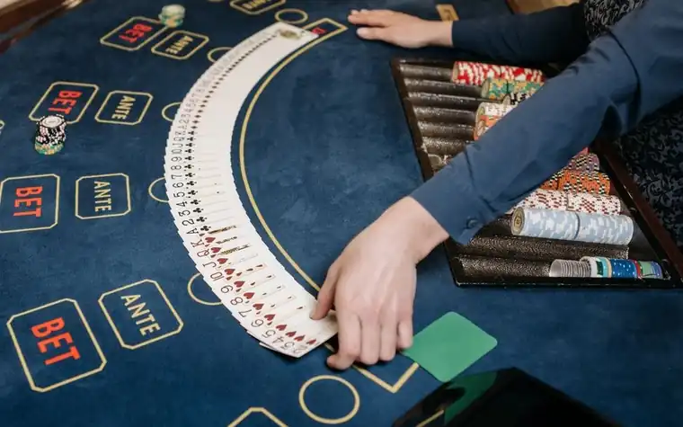A casino felt table marked ANTE and BET with playing cards fanned out during a hand