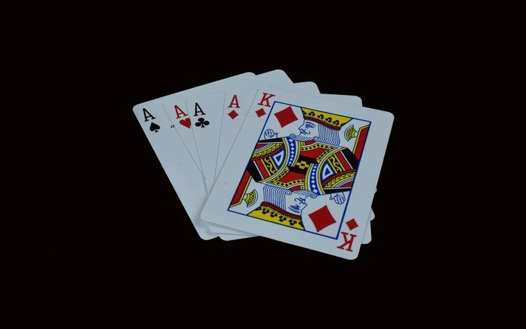 Four aces and the king of diamonds fanned out against a black background
