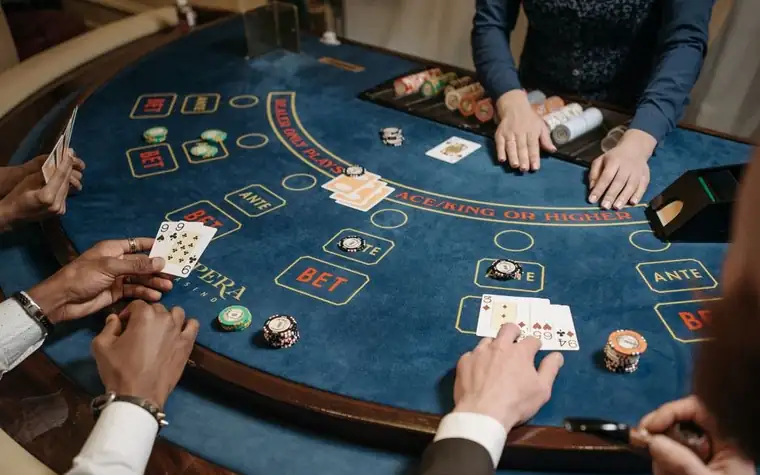 Players at a baccarat table with cards and chips