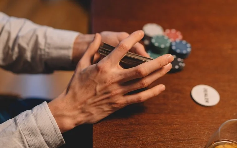 Hands holding playing cards and poker chips