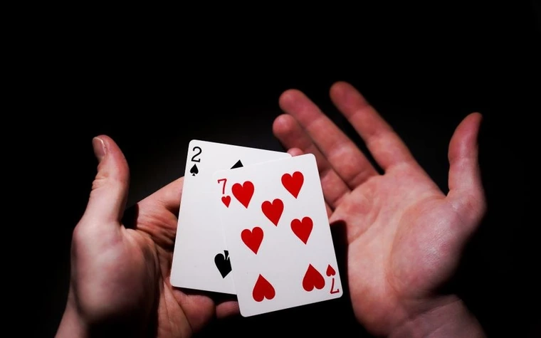 Hands holding playing cards against a dark background