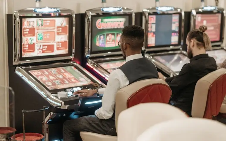 Two players seated at slot machines in a casino
