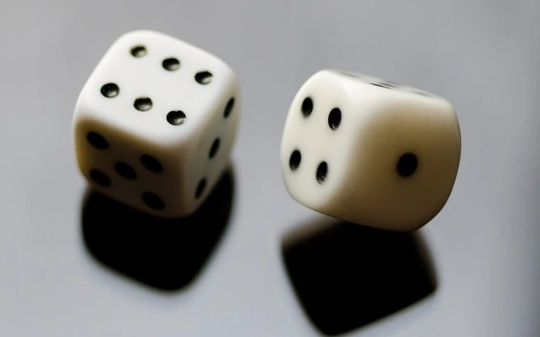 Close-up of two dice mid-roll on a casino table surface
