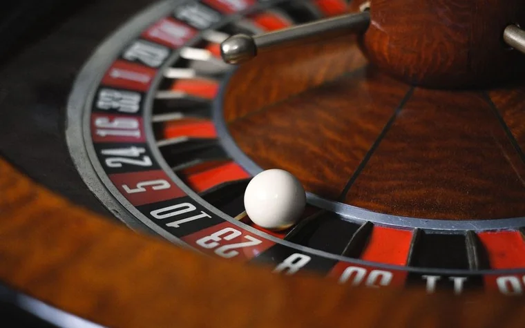 Close-up of a wooden roulette wheel with the ball resting in a red pocket