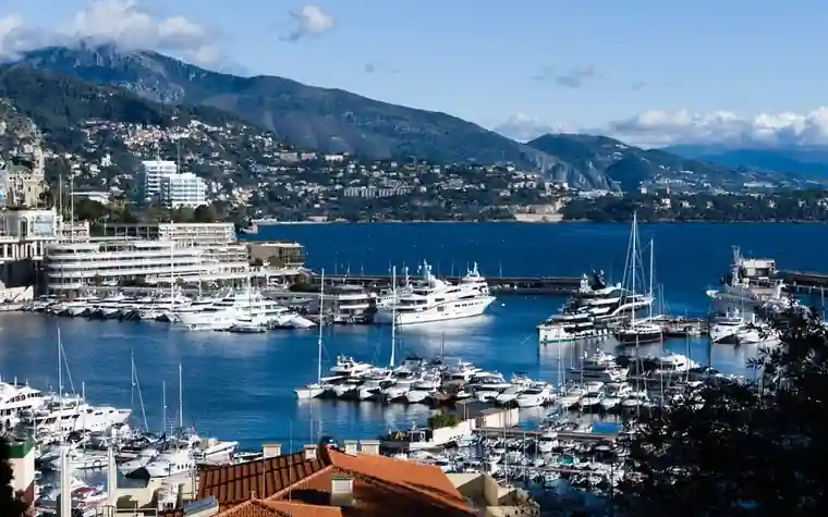 Luxury yachts moored in Monaco's harbor beneath the hillside city