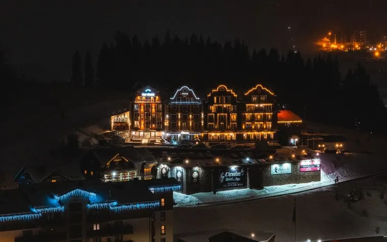 Illuminated mountain resort hotel glowing against snow-covered slopes at night