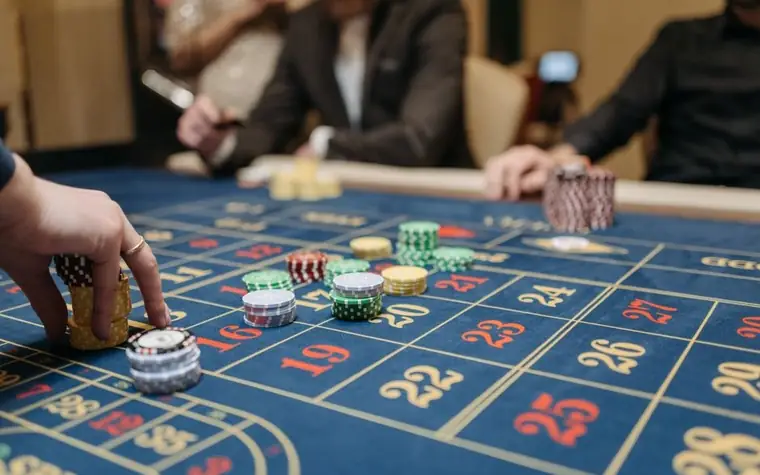 Hands placing casino chips onto a roulette table layout during a game