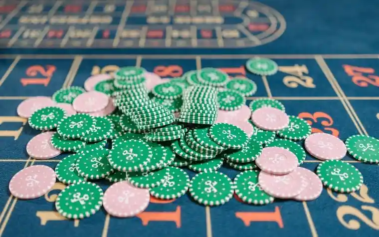 Pile of pink and green casino chips scattered across a roulette table layout