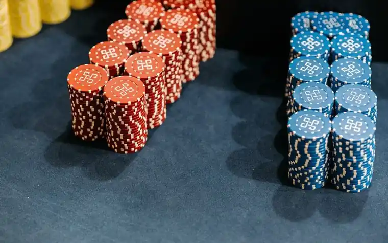 Stacks of red and blue casino chips arranged on a green felt table