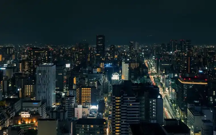 Aerial nighttime view of Osaka's illuminated skyline and waterfront