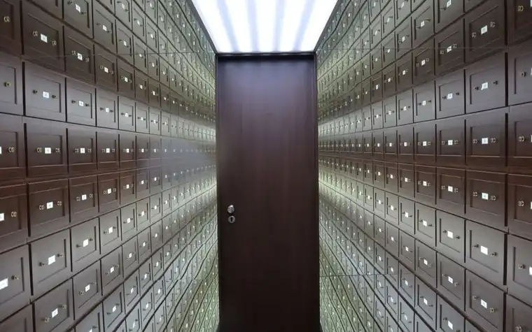 long corridor lined with rows of numbered safe deposit boxes inside a bank vault