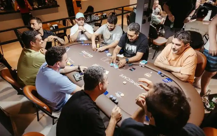 group of players seated around an oval poker table in a casino card room