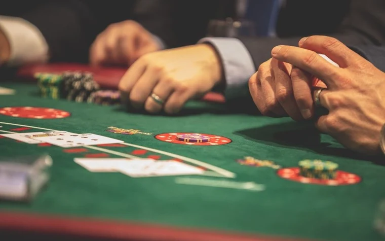 Players' hands and cards on a blackjack table with chips in play