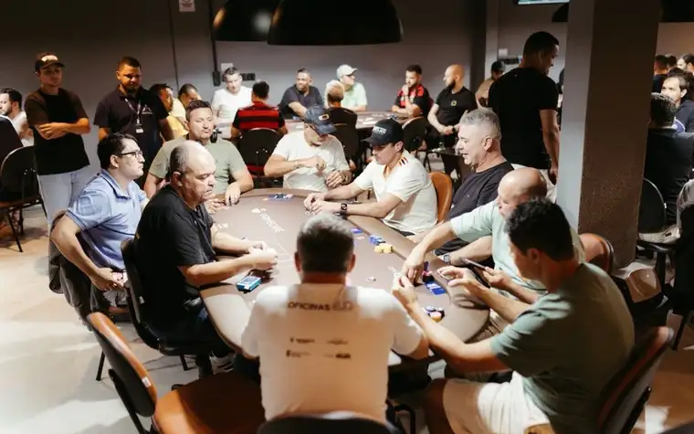 group of players seated around an oval poker table in a casino poker room