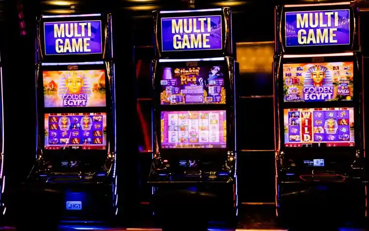 Rows of illuminated slot machines with colorful screens on a casino floor