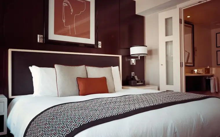 Elegant hotel bedroom with a burgundy accent wall and neatly made bed