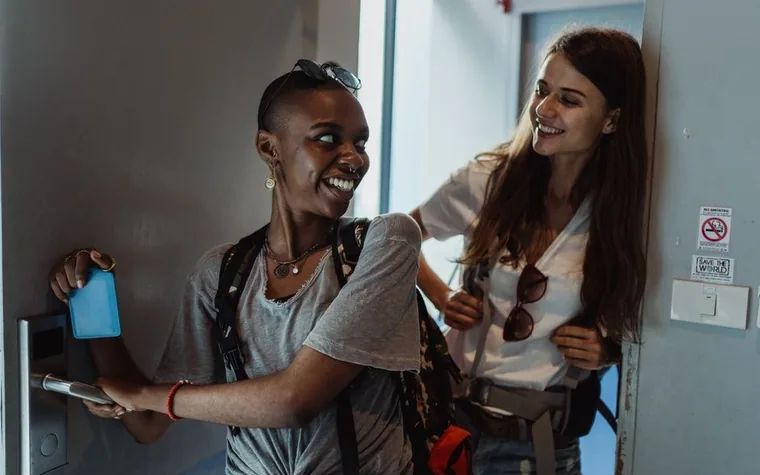 Two guests smiling while unlocking a hotel room door with a key card