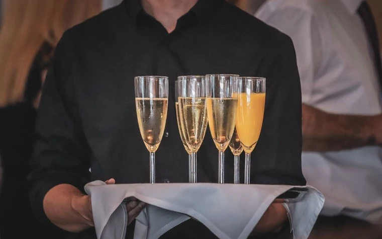 Waiter holding a tray of champagne and orange juice glasses at a hotel event