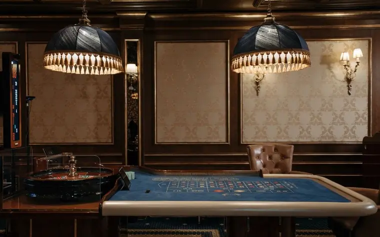 Elegant empty casino gaming floor with a roulette table under pendant lighting