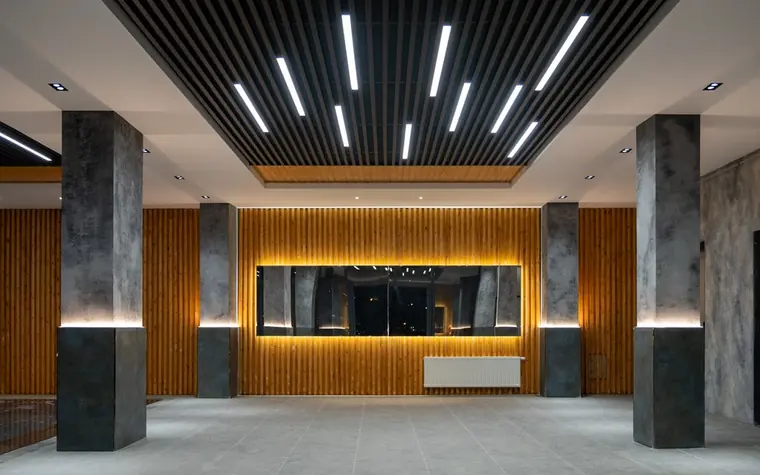 modern casino resort lobby with wood-slat walls, stone columns, and a backlit reception desk at night