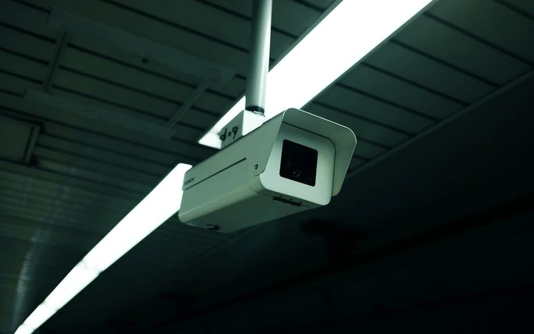 security camera mounted on an angled ceiling bracket inside a dimly lit casino corridor