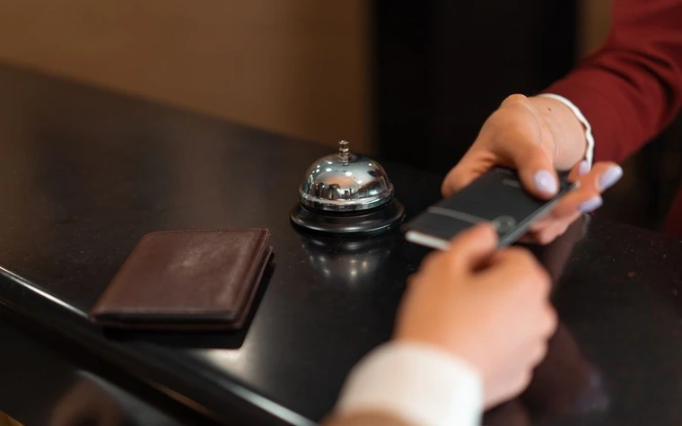 Hotel front desk counter with a service bell, leather wallet and phone during check-in