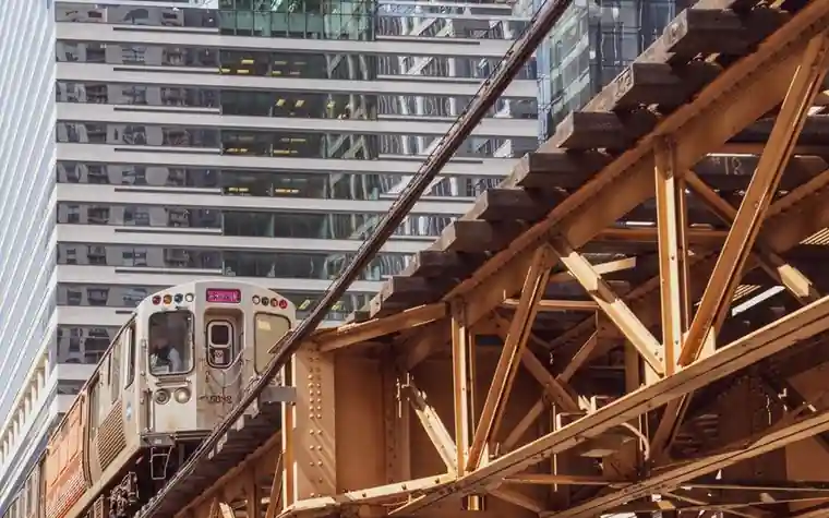 Chicago elevated train rounding a curve on steel trusses between tall downtown buildings