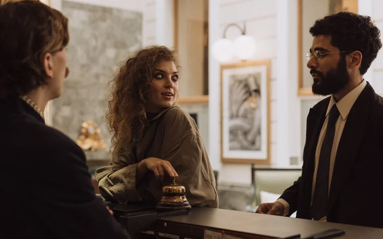 Two guests speaking with a staff member across a hotel reception desk