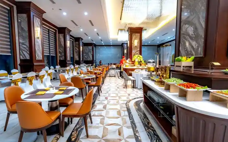 Hotel buffet restaurant with marble floors, round tables and a food display counter