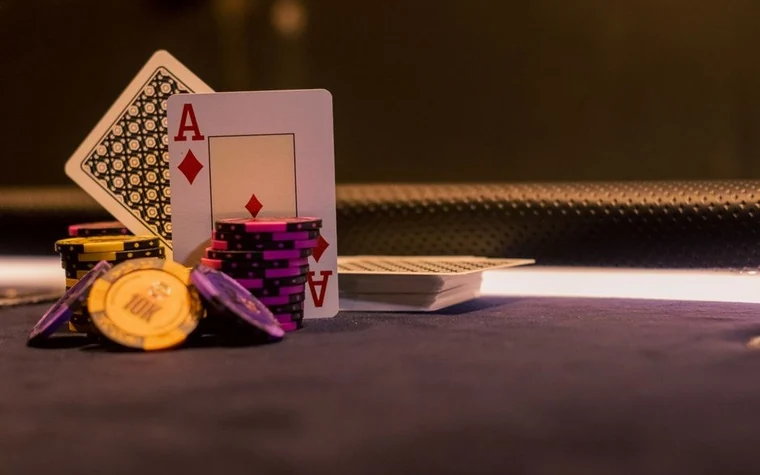 Close-up of poker chips and playing cards arranged on a green casino gaming table